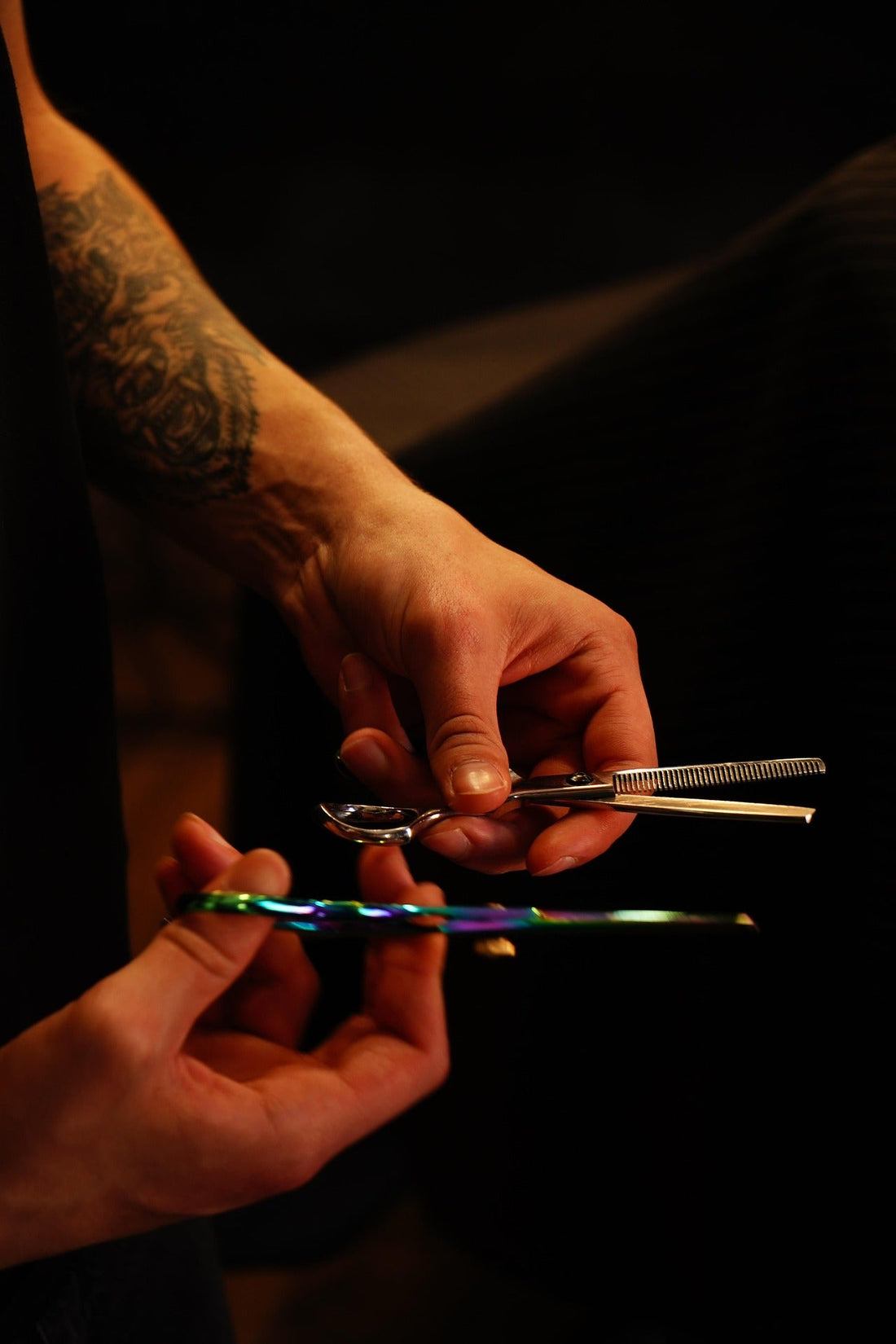 Friseurhände präsentieren verschiedene Haarscherenmodelle für professionelle Haarschnitte.